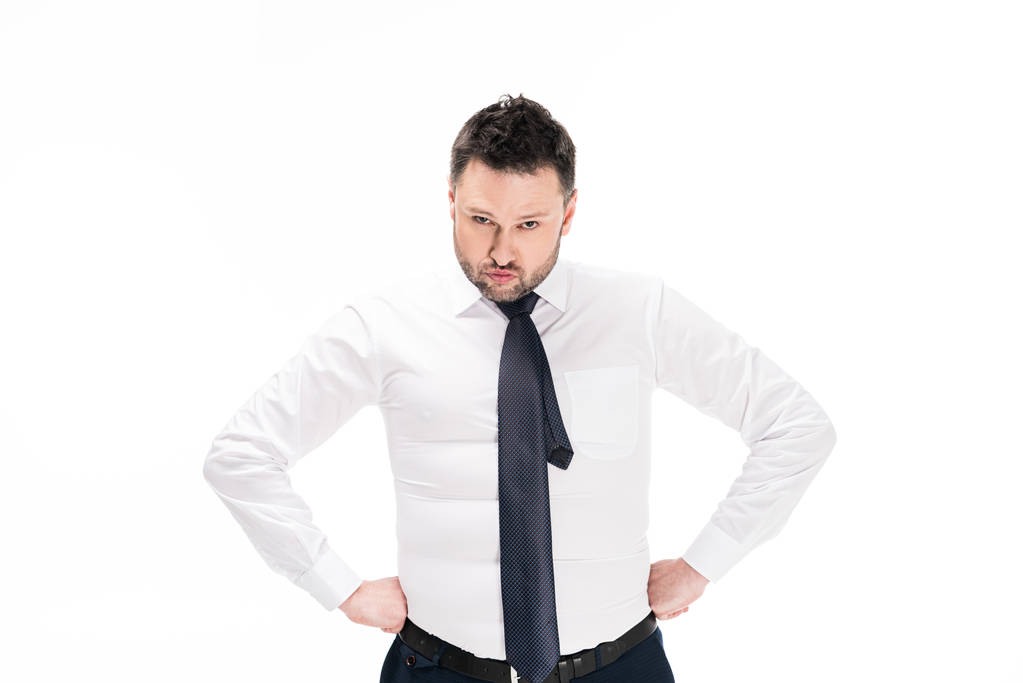 übergewichtiger Mann in enger formaler Kleidung mit den Händen akimbo Blick auf Kamera isoliert auf weiß - Foto, Bild