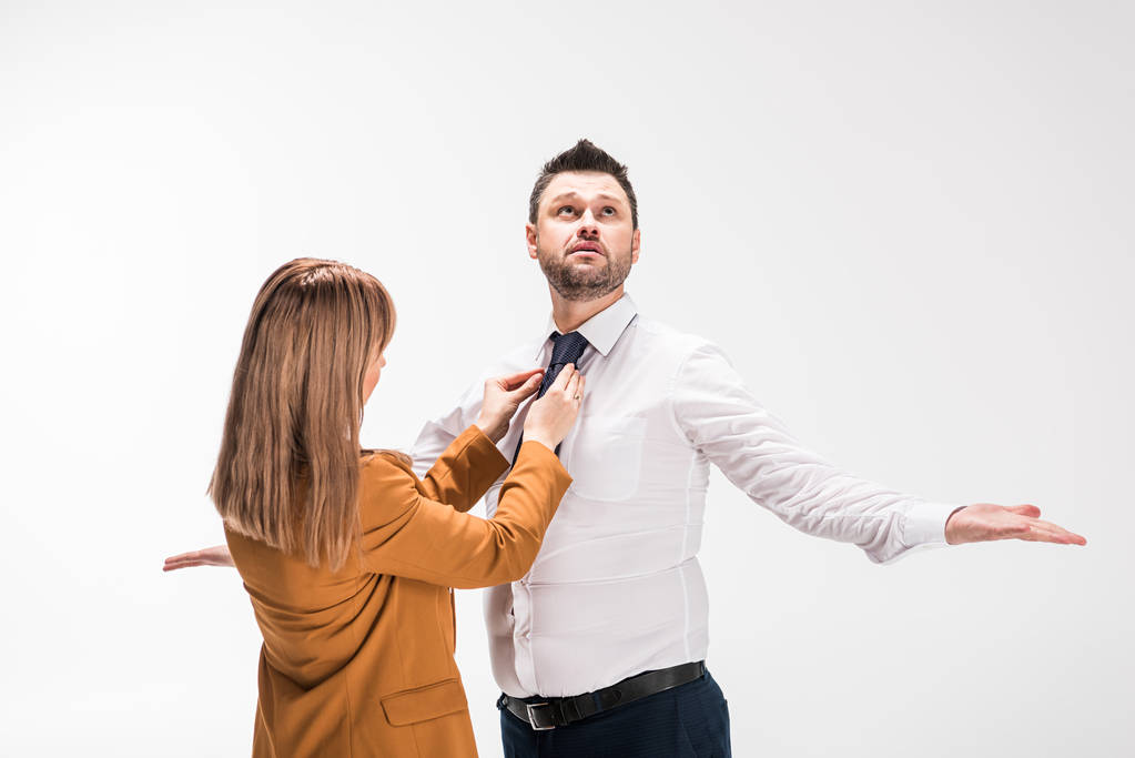 woman in suit adjusting tie of overweight man gesturing with hands isolated on white - 写真・画像