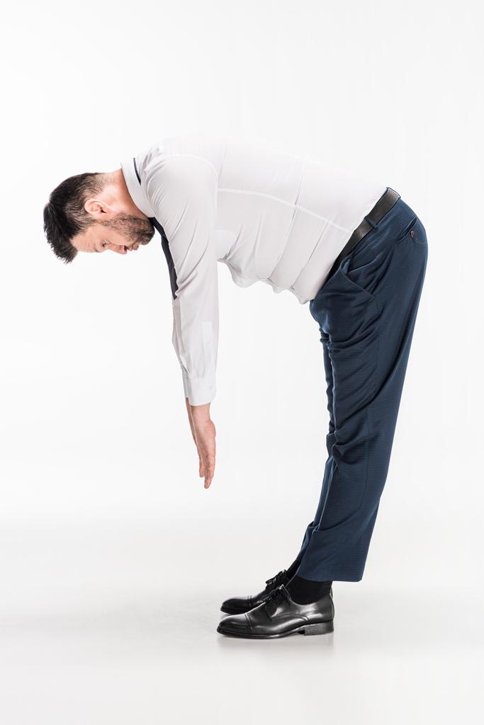 Übergewichtiger Mann in enger formaler Kleidung beugt sich vor und dehnt sich auf weißem Grund - Foto, Bild