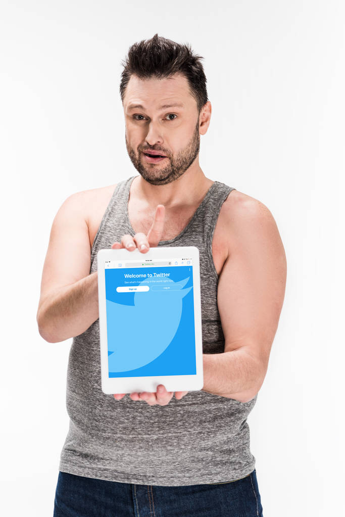 człowiek z nadwagą patrząc na aparat fotograficzny i pokazując cyfrowy tablet z Twitterem aplikacji na ekranie na białym tle - Zdjęcie, obraz