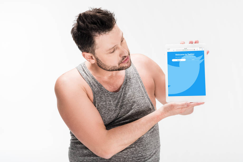 Übergewichtiger Mann zeigt digitales Tablet mit Twitter-App auf weißem Bildschirm - Foto, Bild