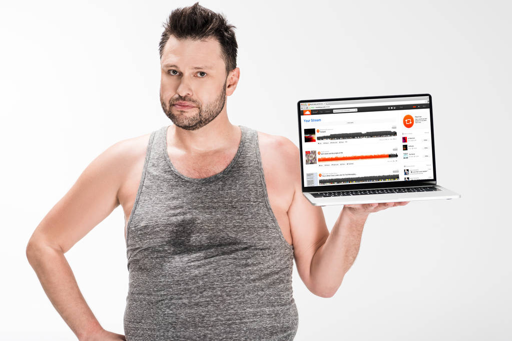 człowiek z nadwagą patrząc na kamerę i trzymając laptopa z SoundCloud stronie internetowej na białym tle na ekranie - Zdjęcie, obraz