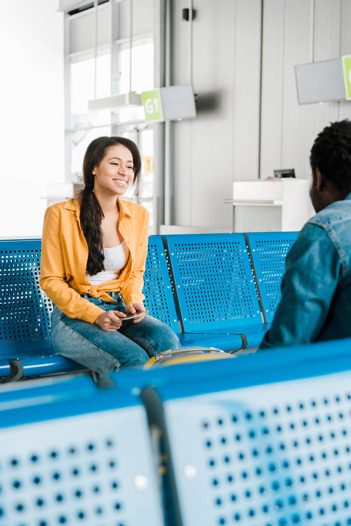 hymyilevä afrikkalainen amerikkalainen nainen istuu lähtöaulassa poikaystävän kanssa
 - Valokuva, kuva