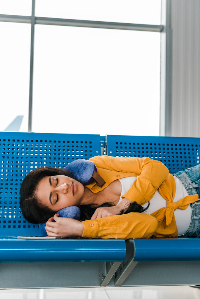 donna afroamericana che dorme su sedili con cuscino da viaggio nella sala partenze
 - Foto, immagini