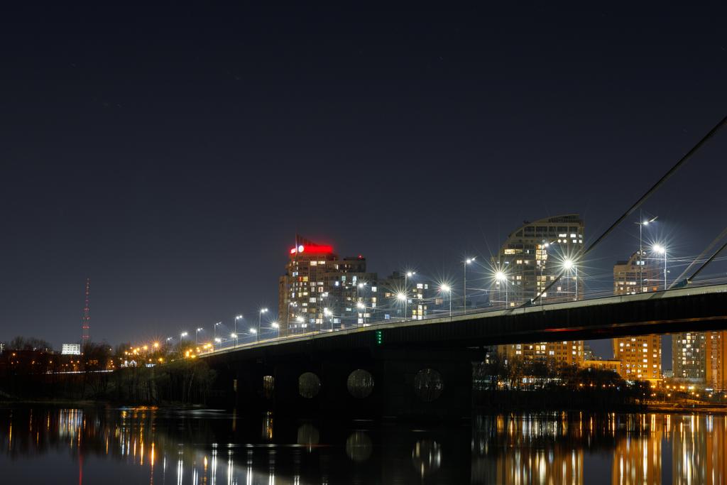 Stadtbild mit beleuchteter Brücke über dem Fluss bei Nacht - Foto, Bild