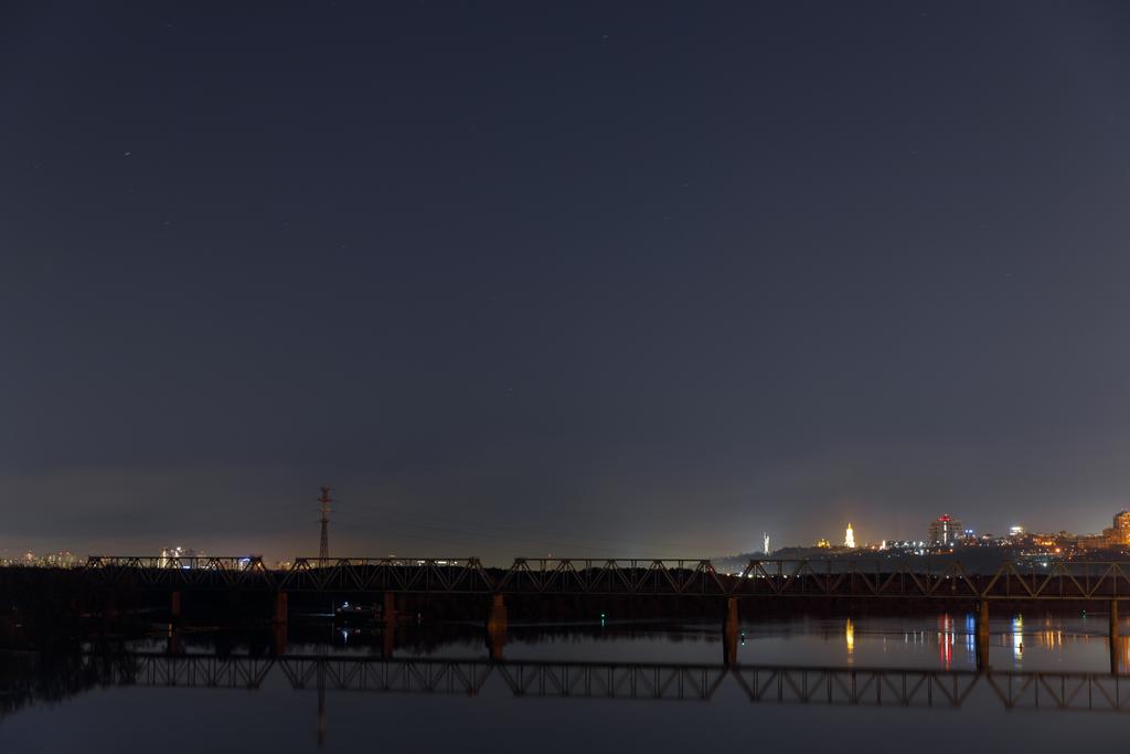 темный городской пейзаж с спокойной рекой и мостом ночью
 - Фото, изображение