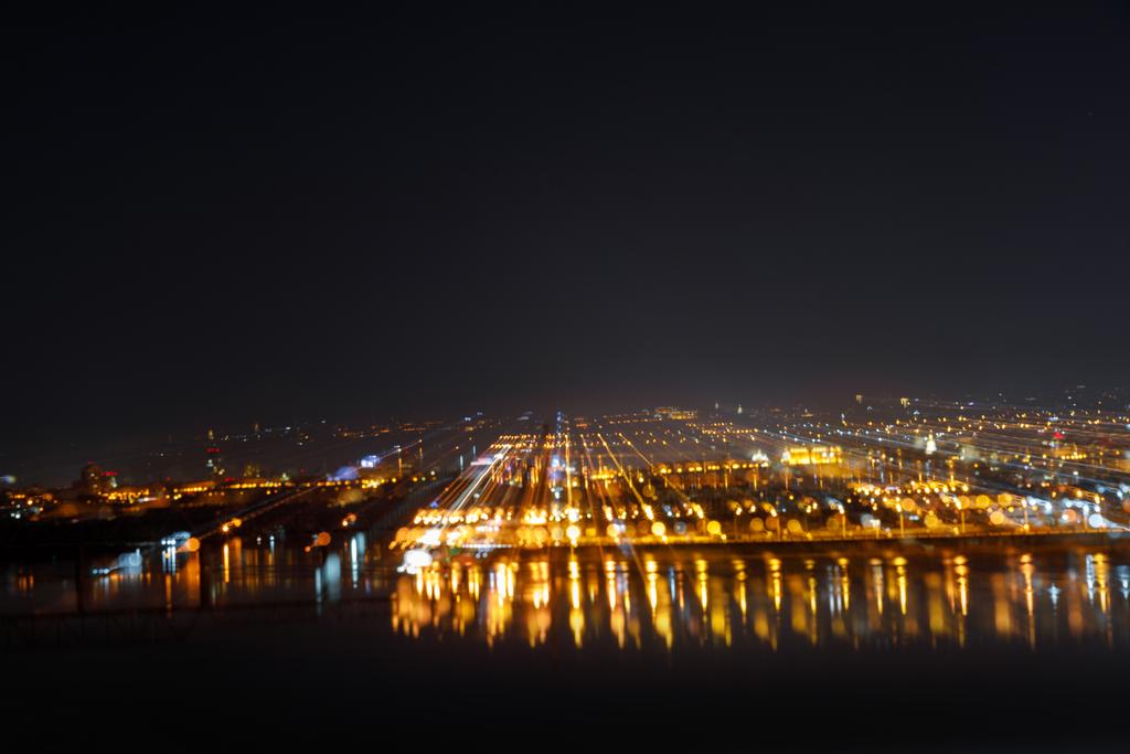 Luftaufnahme dunkler Stadtlandschaft mit beleuchteten Gebäuden bei Nacht - Foto, Bild