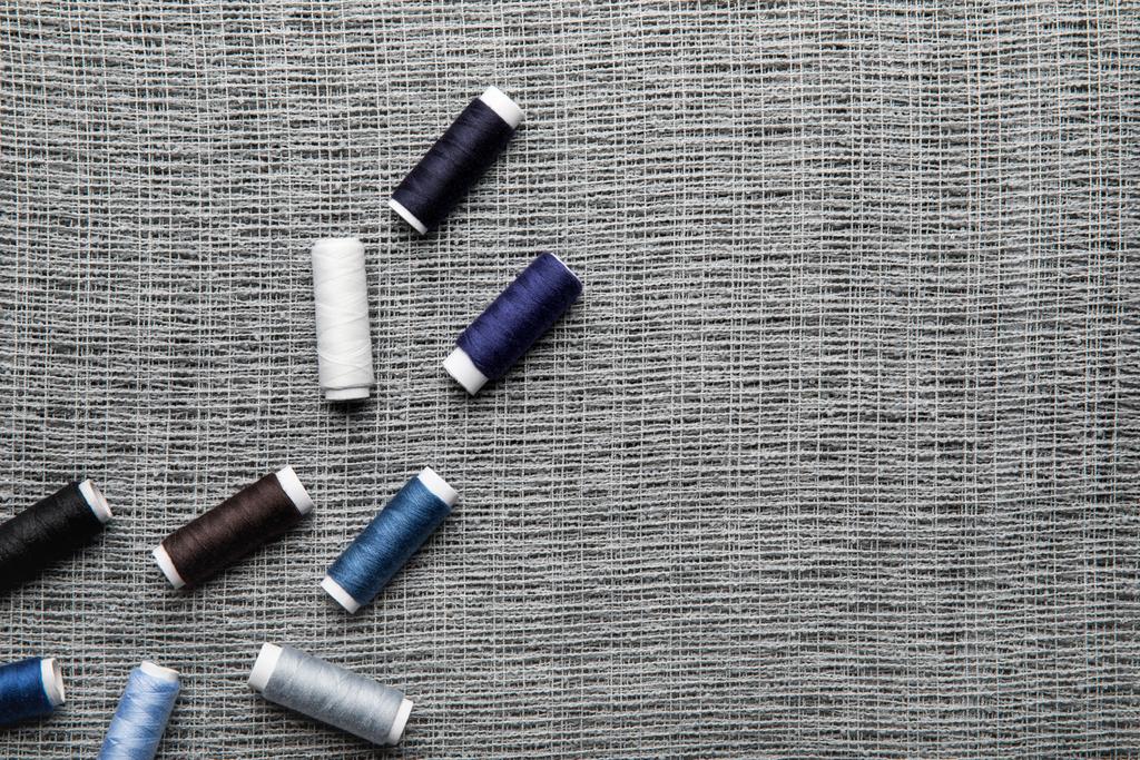 vista superior de bobinas de rosca azul e cinza dispersas em pano de saco com espaço de cópia
 - Foto, Imagem