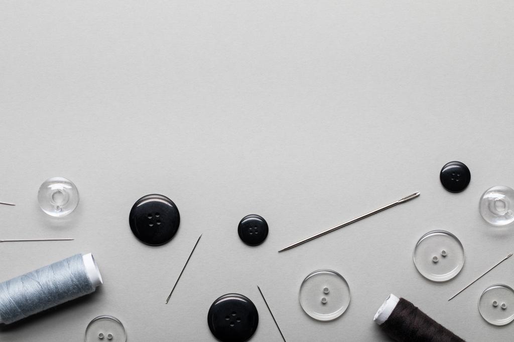 vista superior de botones de ropa, agujas y bobinas de rosca aisladas en gris con espacio para copiar
 - Foto, imagen