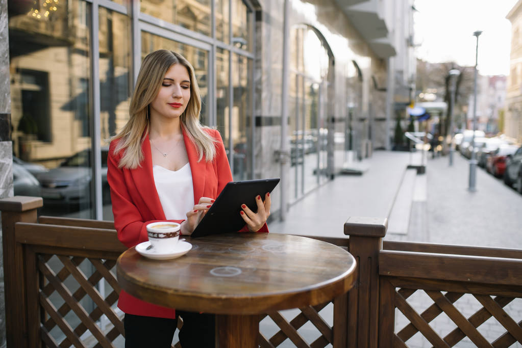 Outdoor stad mode portret van jonge zakenvrouw werken in café op het terras op zonnige dag, Casual stijlvolle outfit, Mint Details, met behulp van haar tablet, café Break, Business concept. - Foto, afbeelding