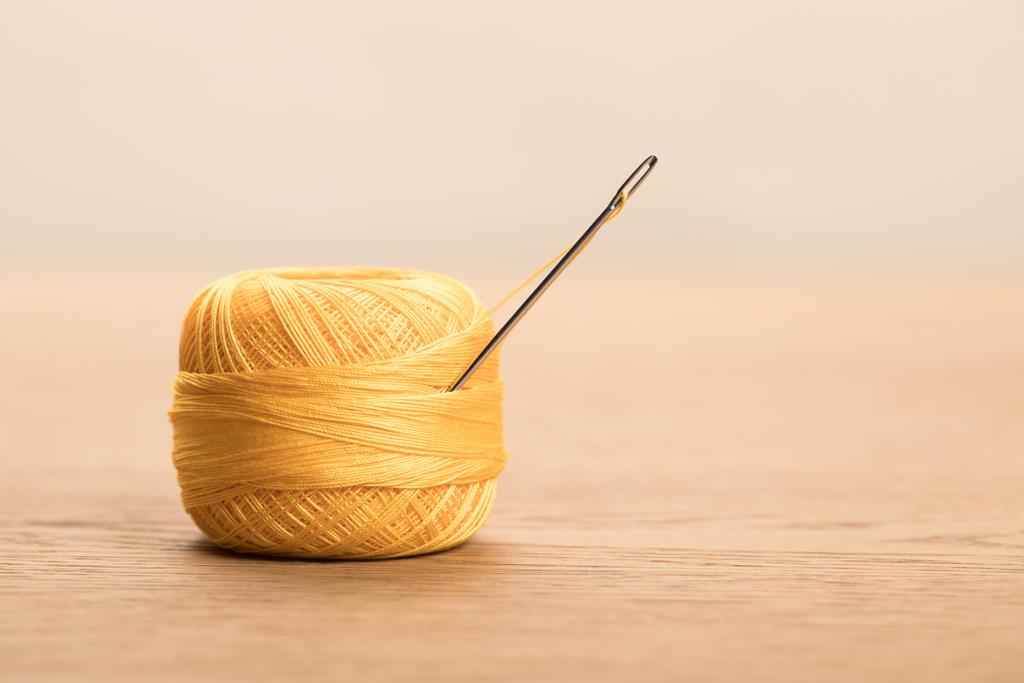 selectieve focus van geel katoen breien garen bal met naald geïsoleerd op beige met kopieerruimte - Foto, afbeelding