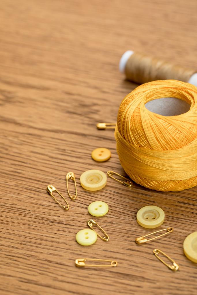 coton tricot boule de fil avec des boutons de vêtements et des épingles de sécurité sur table en bois
 - Photo, image