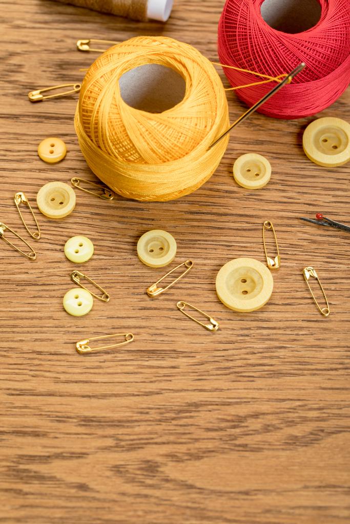 bawełniane kulki dziewiarskie z guzikami odzieży i pinami bezpieczeństwa na drewnianym stole z kopią - Zdjęcie, obraz