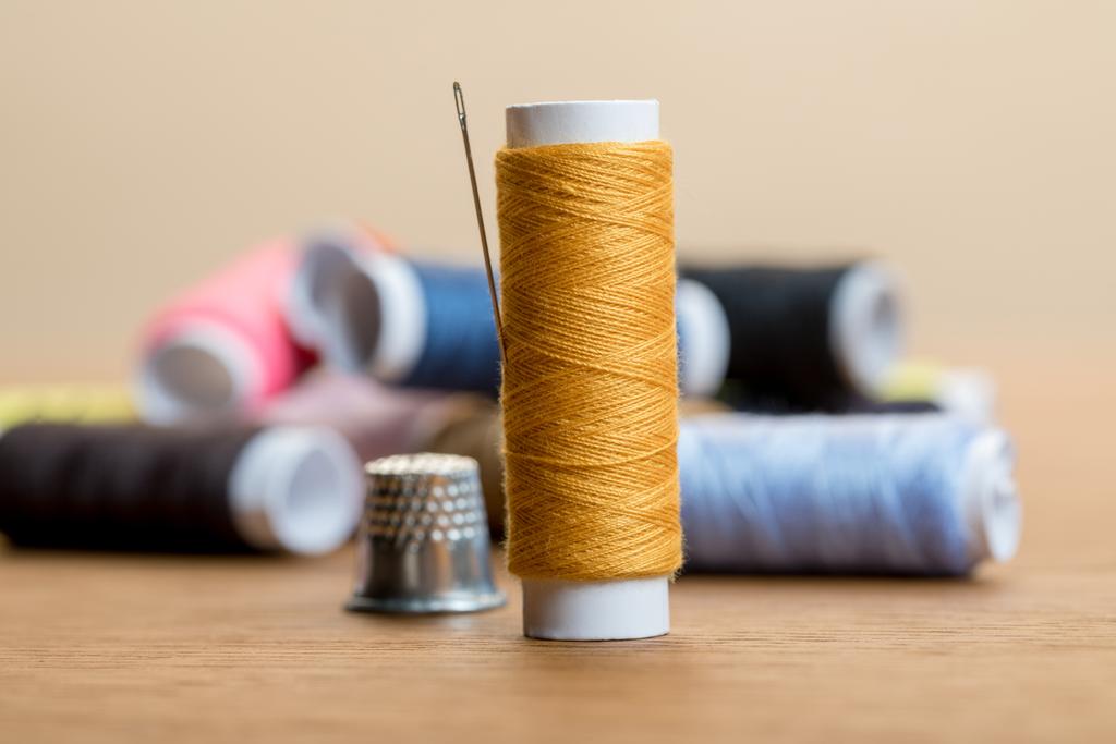 enfoque selectivo de bobina de hilo de algodón con aguja aislada en beige
 - Foto, imagen