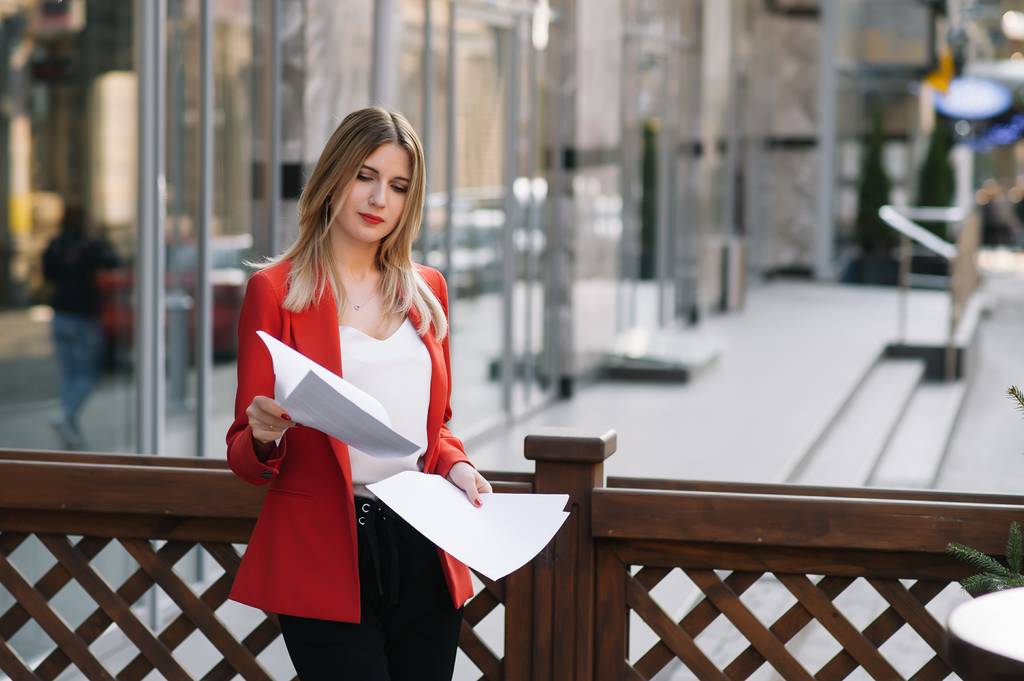 Portrait of business women in feeling of concentrate stress and see stand and hold the paper file sheet in the outdoor pedestrian walk way with the city space of exterior modern facade building - Photo, Image