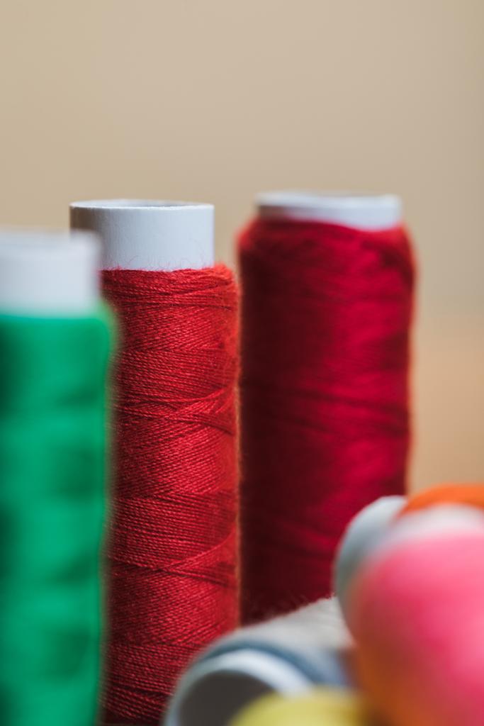 enfoque selectivo de bobinas de hilo de algodón rojo aisladas en beige
 - Foto, imagen