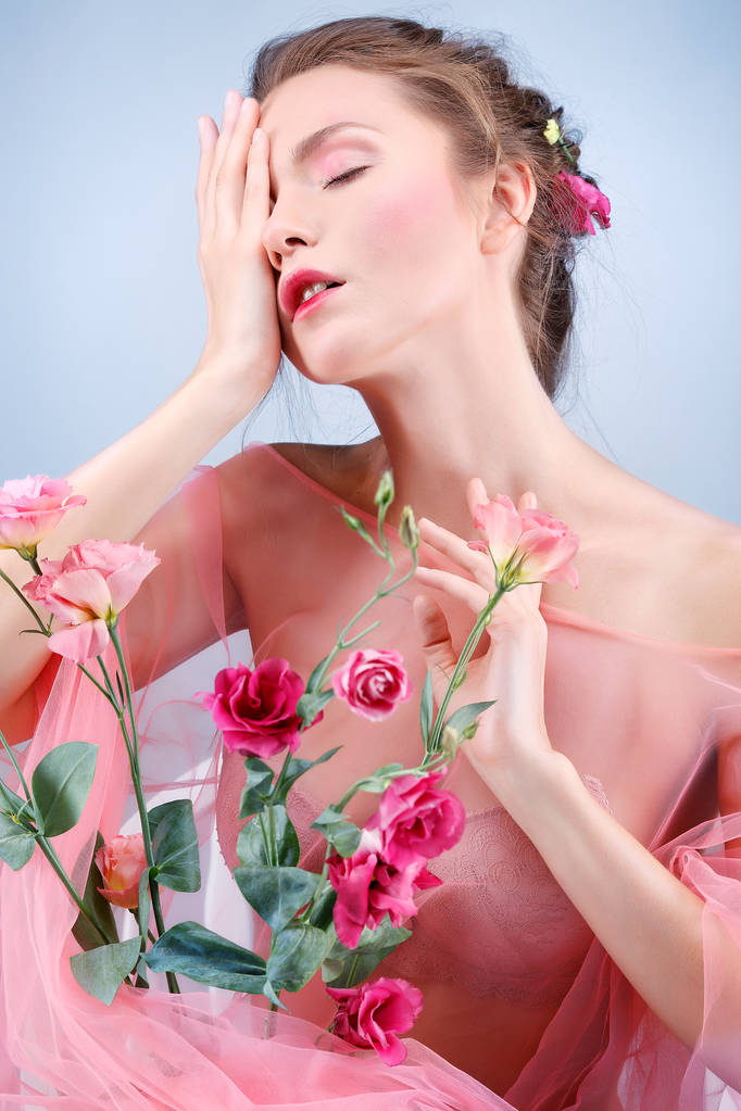 Krásná dívka, izolovaná na modrém pozadí s pestrobarevnou květenkou, emocemi, kosmetikou - Fotografie, Obrázek