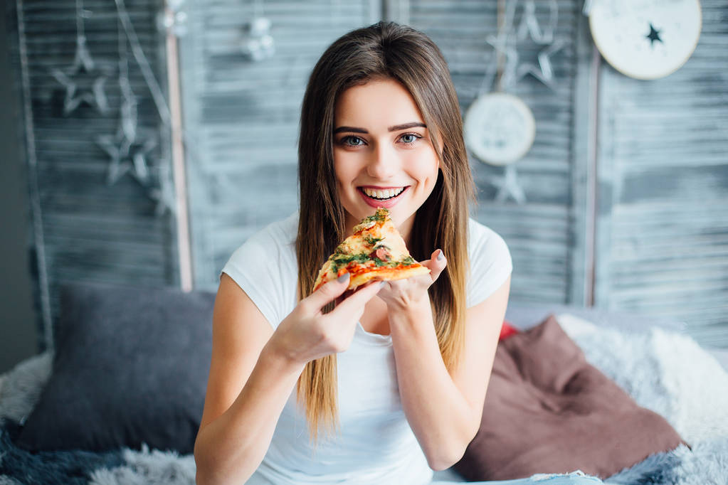 Mooie jonge vrouw eten pizza, focus op de voorgrond - Foto, afbeelding