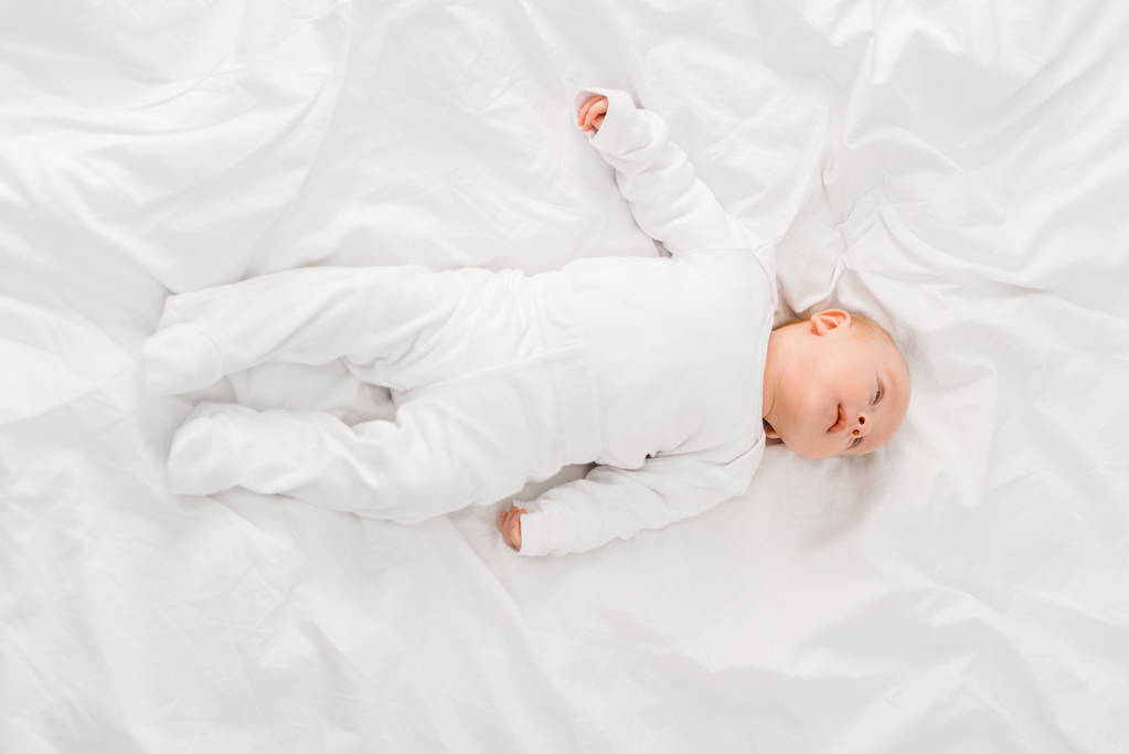 Κορυφαία θέα του βρέφους μωρό που βρίσκεται σε λευκό φύλλο - Φωτογραφία, εικόνα