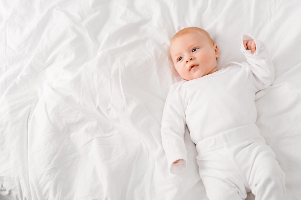 Κορυφαία θέα του βρέφους μωρό που βρίσκεται σε λευκό φύλλο - Φωτογραφία, εικόνα