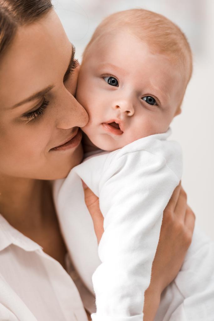 madre en camisa blanca sosteniendo al bebé en casa
 - Foto, imagen