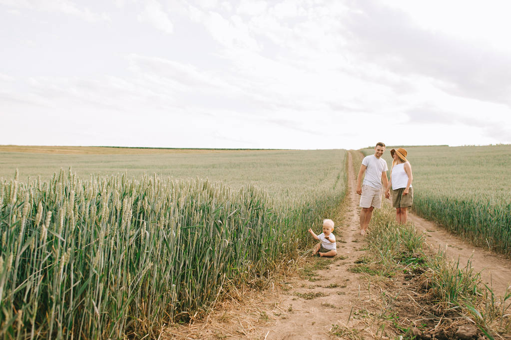 Una familia joven se divierte con su pequeño bebé en el campo
 - Foto, Imagen