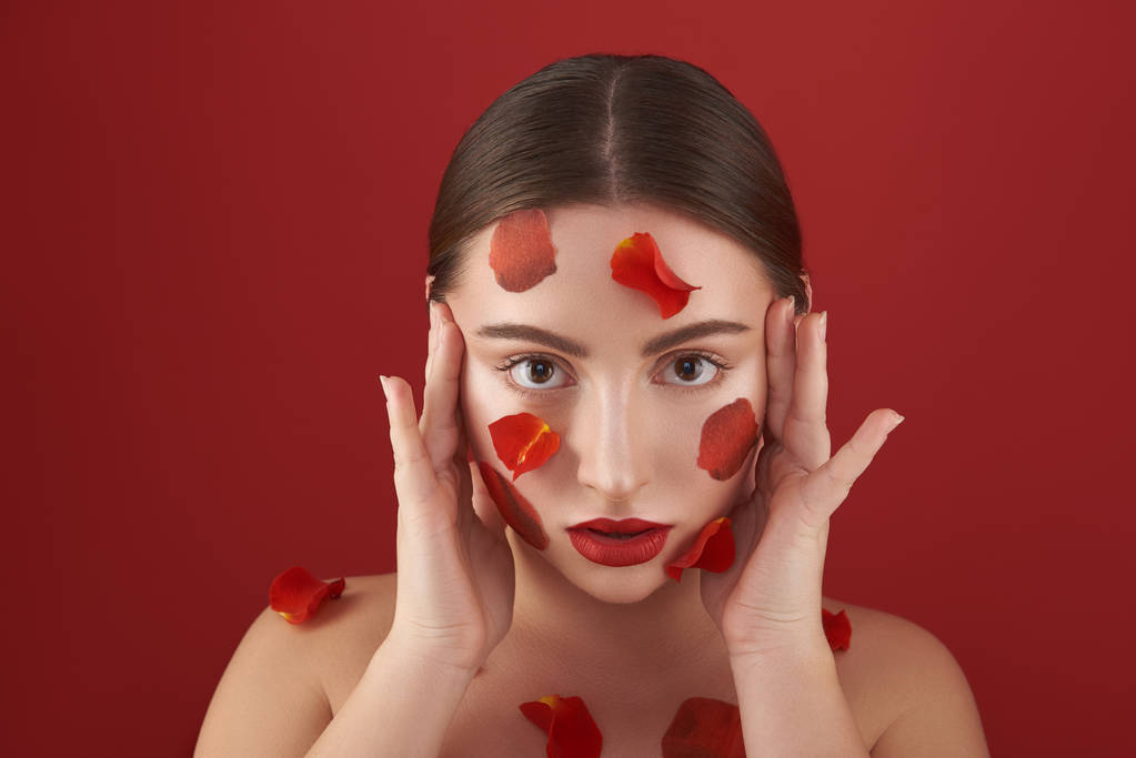 Woman with flower petals on the face touching her temples - 写真・画像