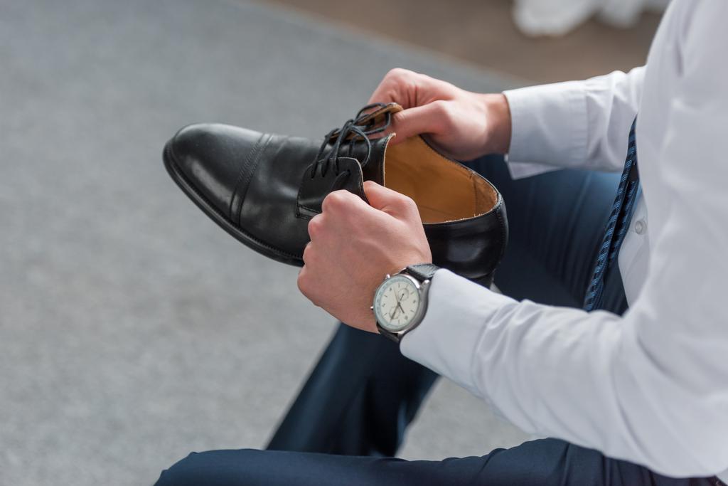 vágott kilátás az ember tartja a fekete cipő a kezében  - Fotó, kép
