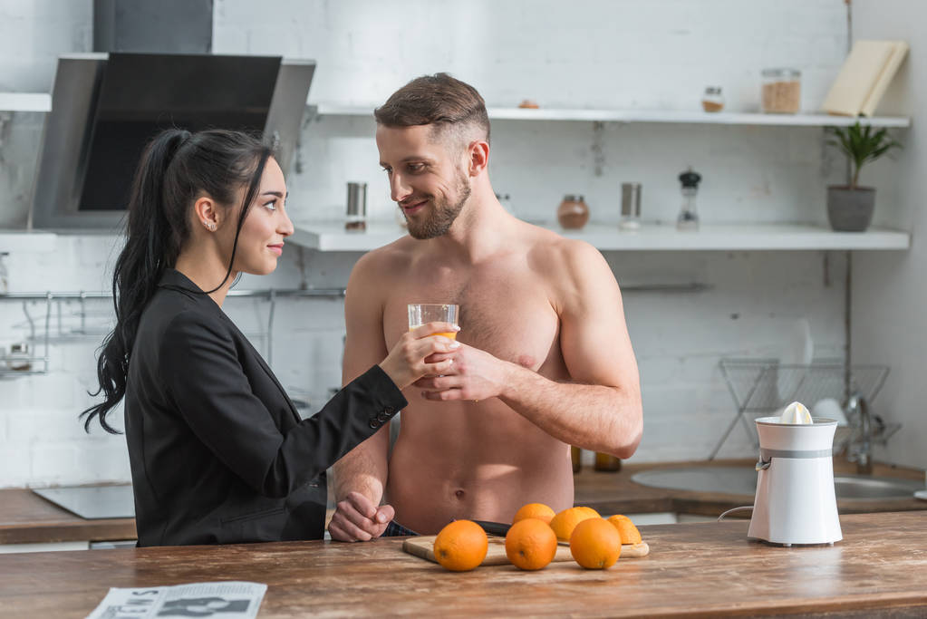 Brodaty muskularny Człowiek dając szklankę świeżego soku pomarańczowego do atrakcyjnej dziewczyny  - Zdjęcie, obraz