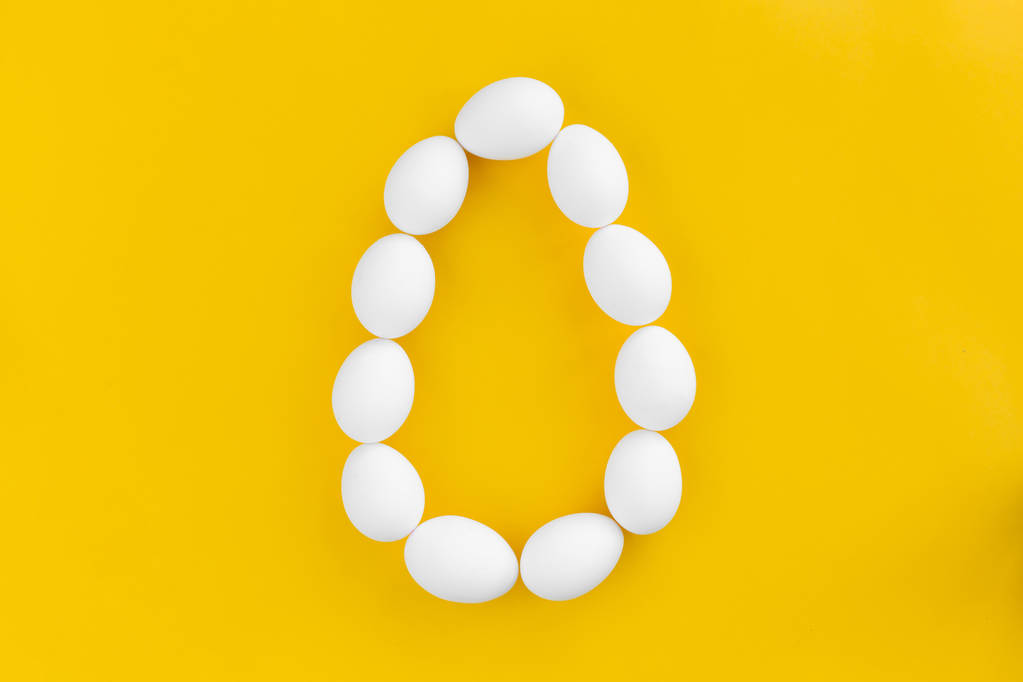 Білі курячі яйця лежать у формі великого яйця на жовтому фоні. Концепція здорової органічної їжі та дієти. Великодня тема
 - Фото, зображення