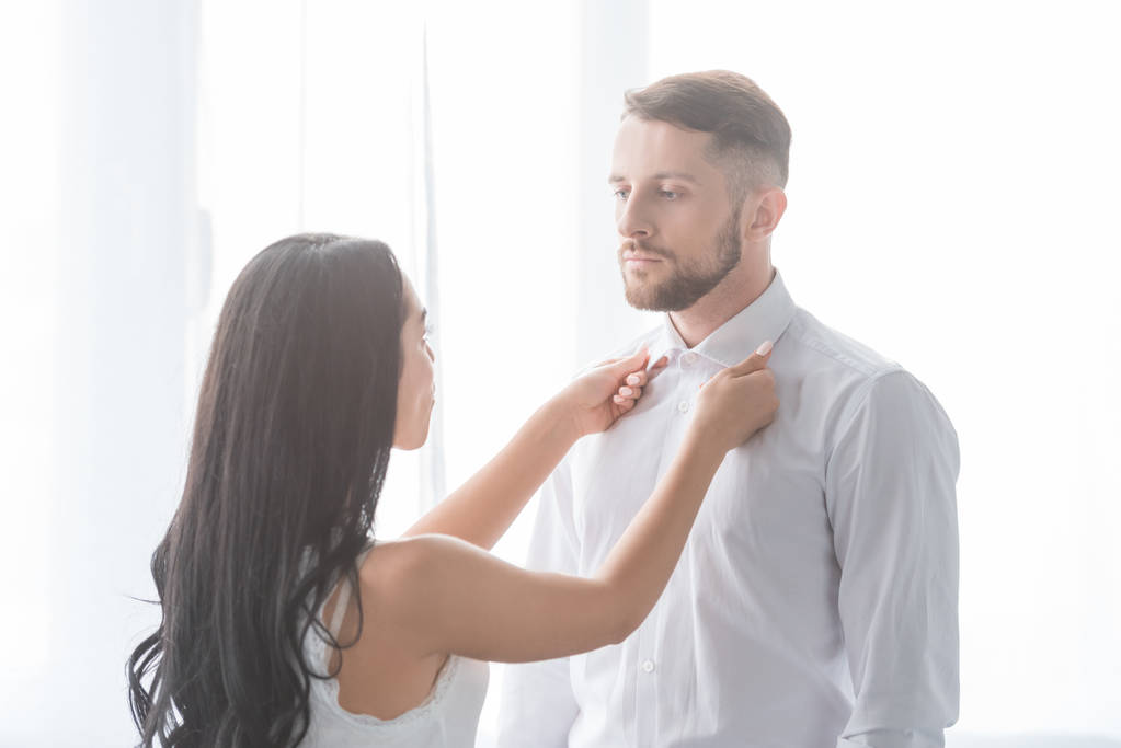 brunette femme touchant les colliers de bel homme en chemise blanche
  - Photo, image