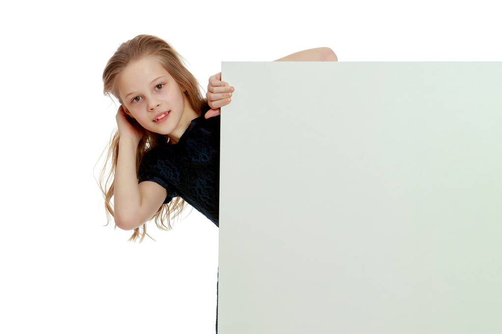 Маленькая девочка смотрит из-за пустого плаката. - Фото, изображение