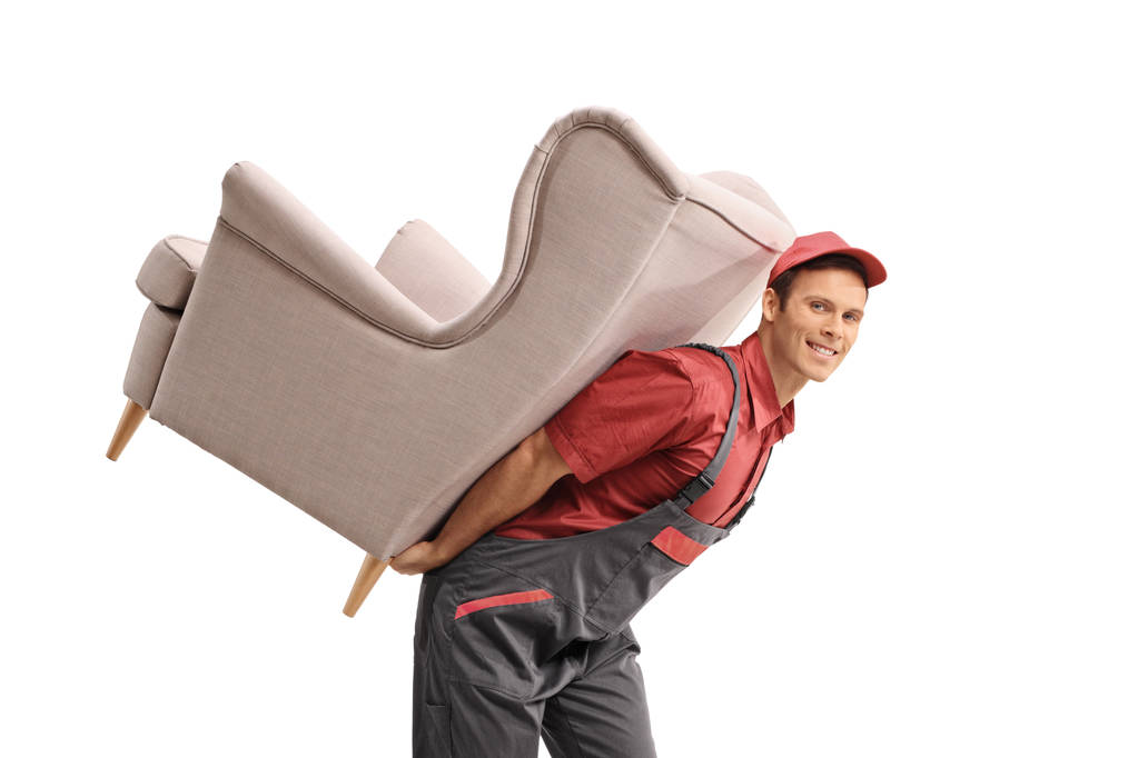 Νέος, κουβαλώντας μια πολυθρόνα στην πλάτη του, απομονωμένη σε λευκό φόντο. - Φωτογραφία, εικόνα