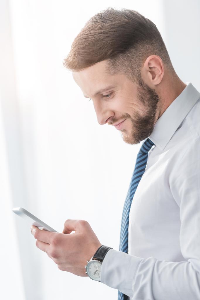 cheerful bearded man in suit smiling while using smartphone  - Photo, Image