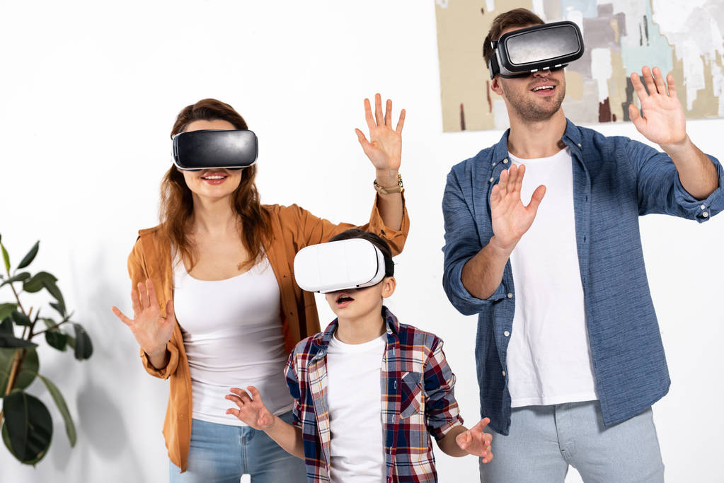 happy parents and cute kid wearing virtual reality headsets at home  - Photo, Image