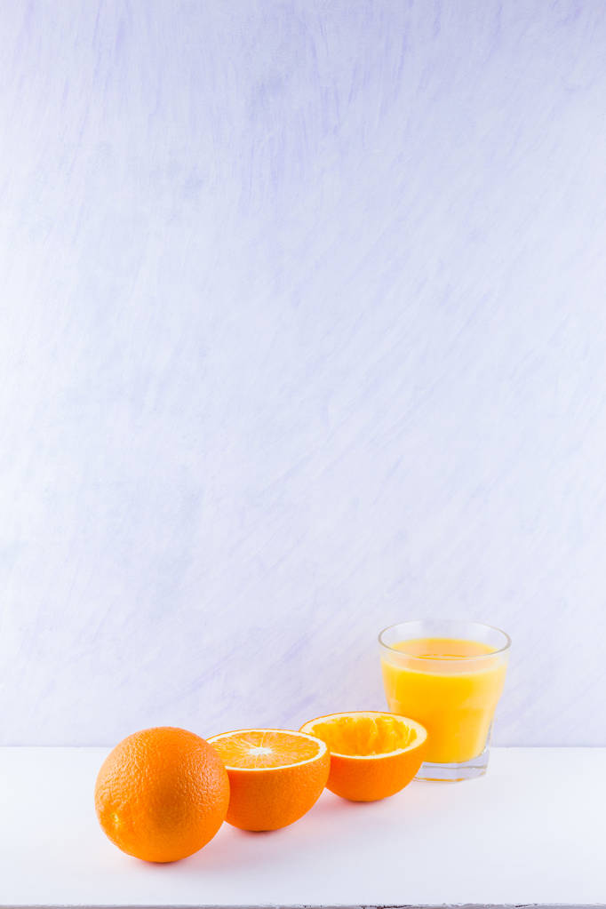 Помаранчеві фрукти з соком, концепція. Апельсиновий сік і половинки апельсинів на білому тлі. Цитрусові для приготування соку. Цілі і стиснуті апельсини і склянка соку
 - Фото, зображення