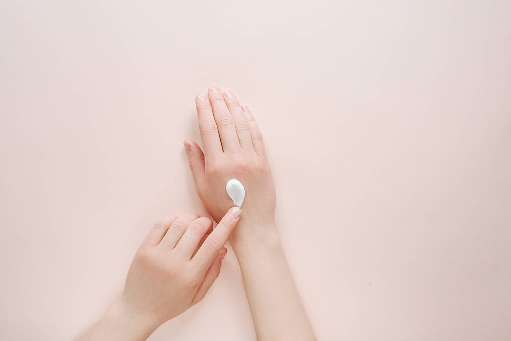 Nő hidratáló kezét a kozmetikai krém krém a másolási hely egy bézs háttérrel. Szépség kozmetikai kutatás és fejlesztés koncepcióját. Felülnézet - Fotó, kép