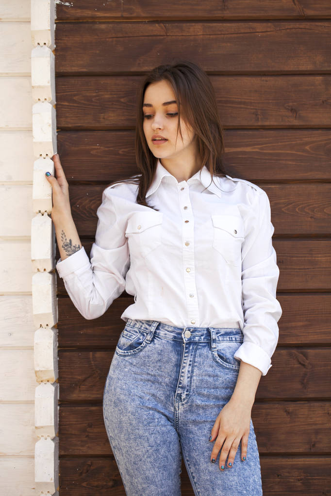 Gelukkig tiener meisje in een wit overhemd op een houten muur achtergrond - Foto, afbeelding