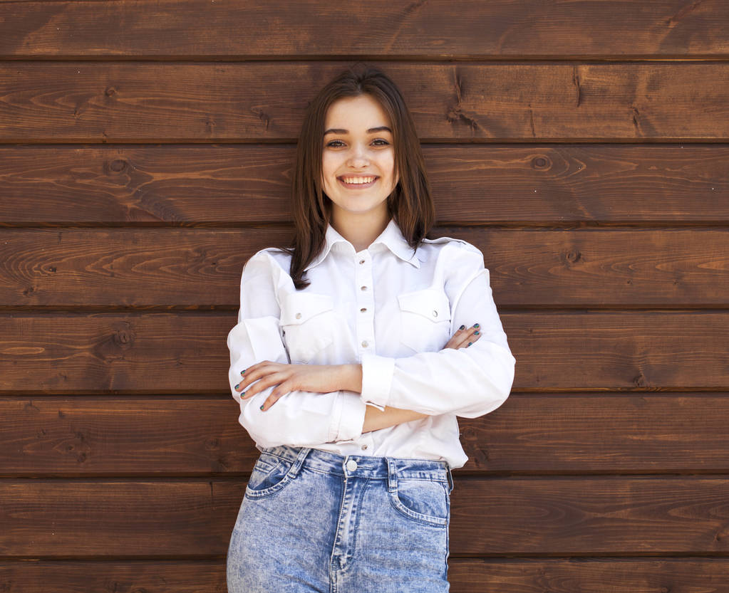 Onnellinen teini tyttö valkoinen paita puinen seinä tausta
 - Valokuva, kuva