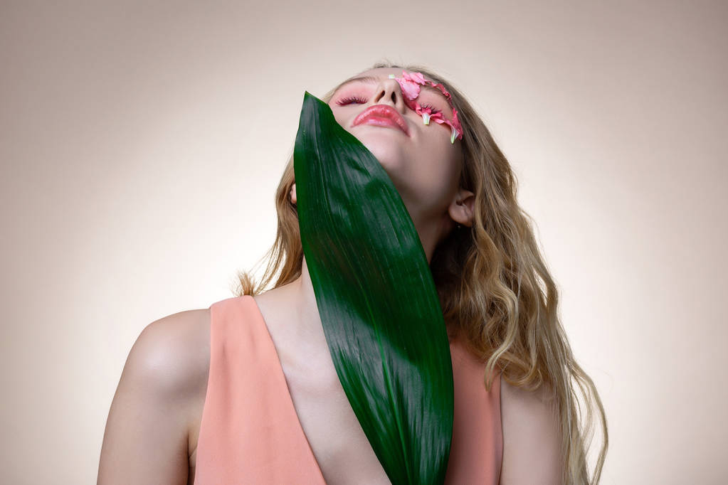 Yaprak ile poz verirken kafasını yükselterek ışık pembe elbise giyen model - Fotoğraf, Görsel