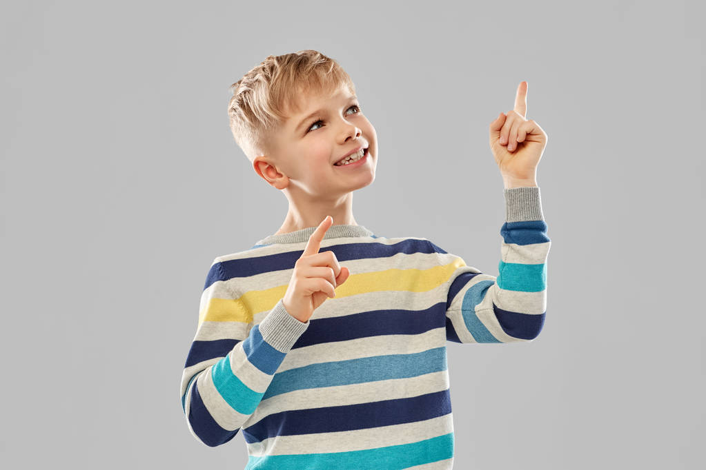 niño pequeño en jersey a rayas apuntando con el dedo hacia arriba
 - Foto, Imagen