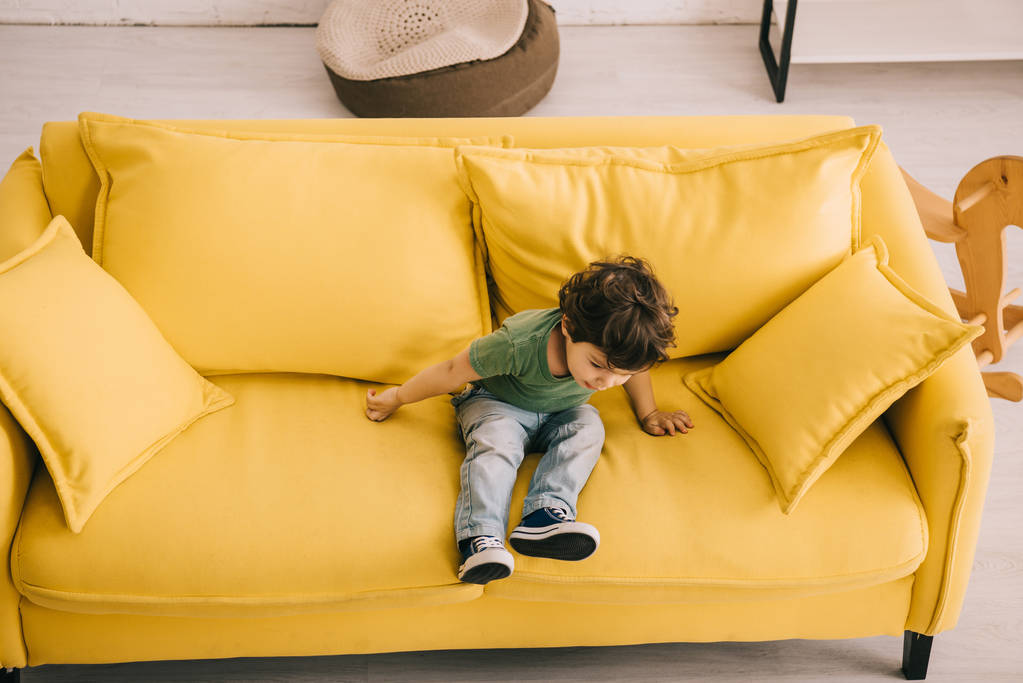 Petit garçon en t-shirt vert assis sur canapé jaune
 - Photo, image