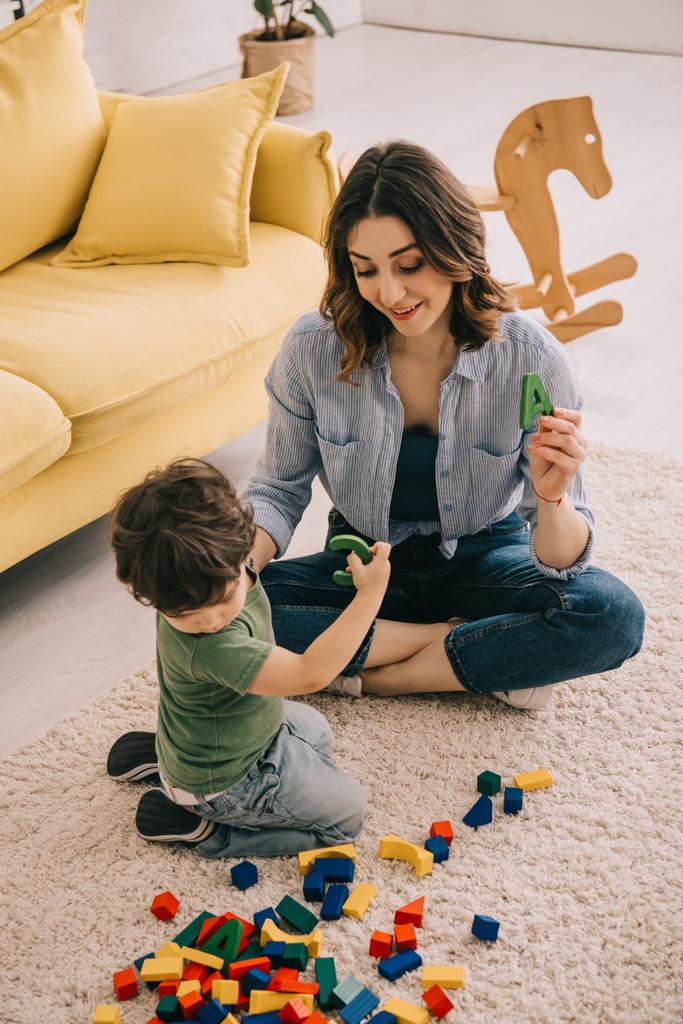 Mère et fils jouant avec des blocs de jouets sur le tapis
 - Photo, image