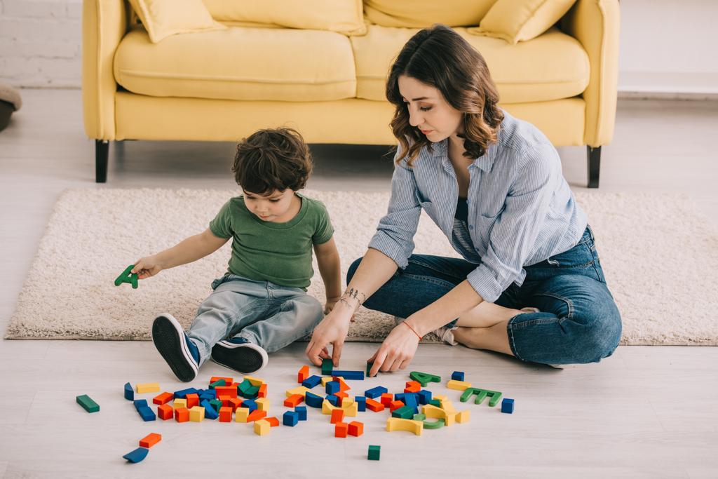 Mother and son playing with toy blocks on carpet - Photo, Image