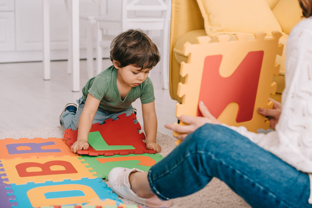 Vista recortada de la madre y el hijo jugando con el alfabeto alfombra del rompecabezas
 - Foto, Imagen