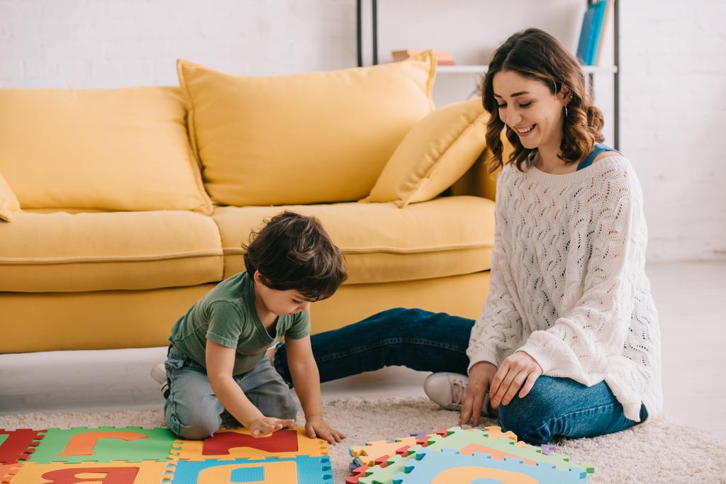 Mosolygó anya és gyerek játszik ABC-puzzle mat - Fotó, kép