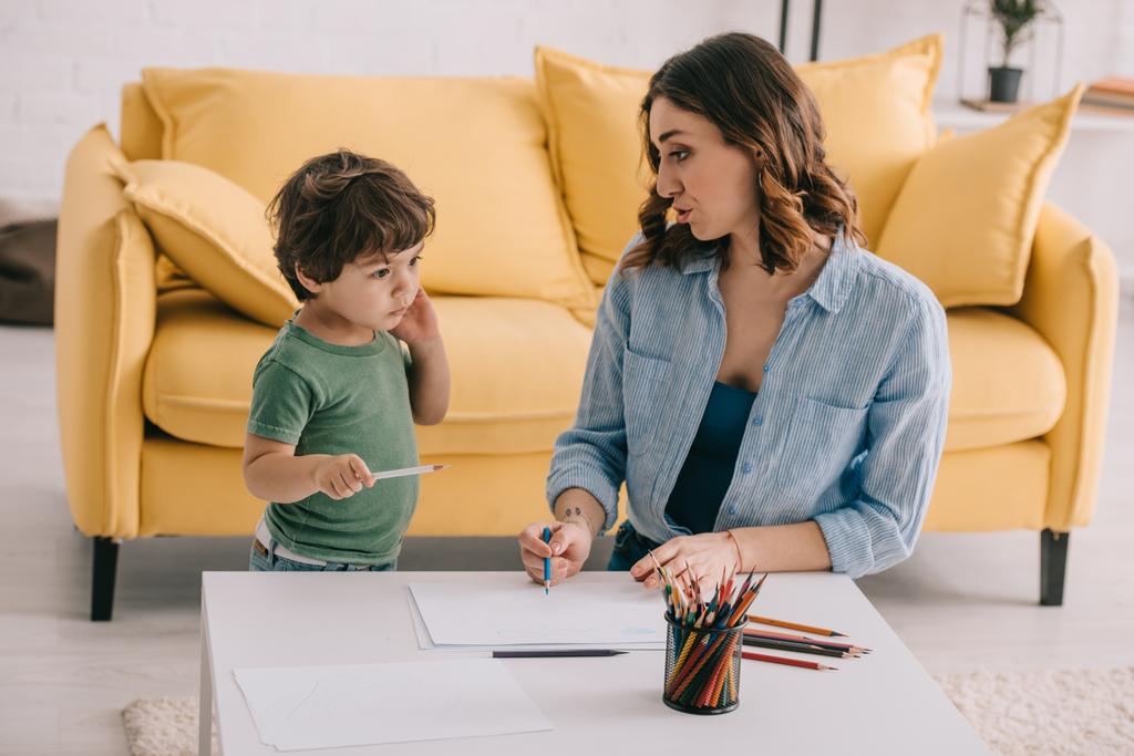 Мати і син малюють кольоровими олівцями у вітальні
 - Фото, зображення