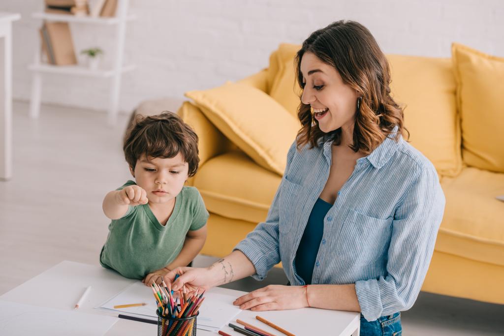 excited mother and son drawing with color pencils in living room - Photo, Image