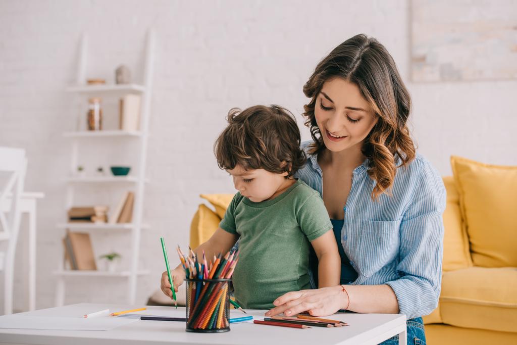 Μητέρα και γιός σχέδιο με χρωματιστά μολύβια στο σαλόνι - Φωτογραφία, εικόνα