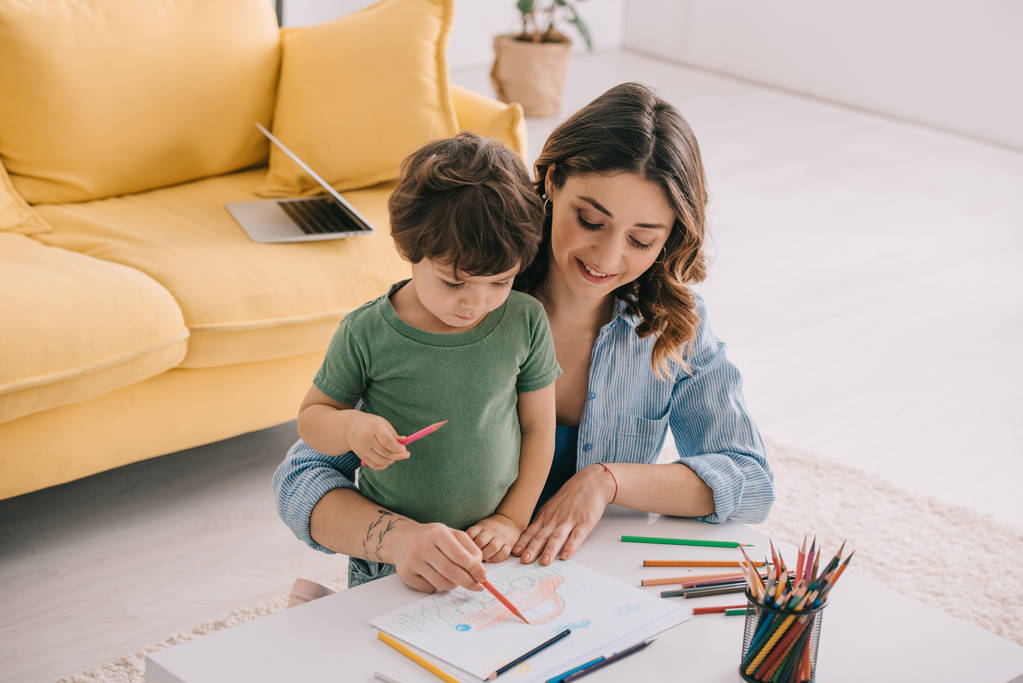Madre e hijo dibujando con lápices de color en la sala de estar
 - Foto, imagen